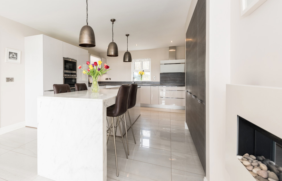 Foto di una cucina minimalista con ante lisce, ante bianche, top in marmo, elettrodomestici in acciaio inossidabile e pavimento in gres porcellanato