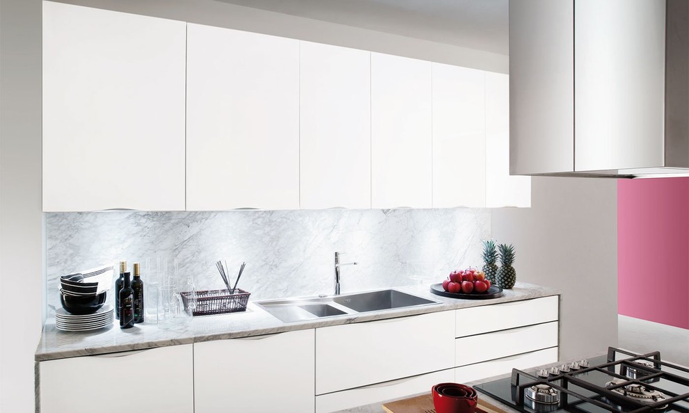 Modern inredning av ett mycket stort kök, med en nedsänkt diskho, luckor med glaspanel, vita skåp, marmorbänkskiva, grått stänkskydd, stänkskydd i marmor, rostfria vitvaror, en köksö och vitt golv