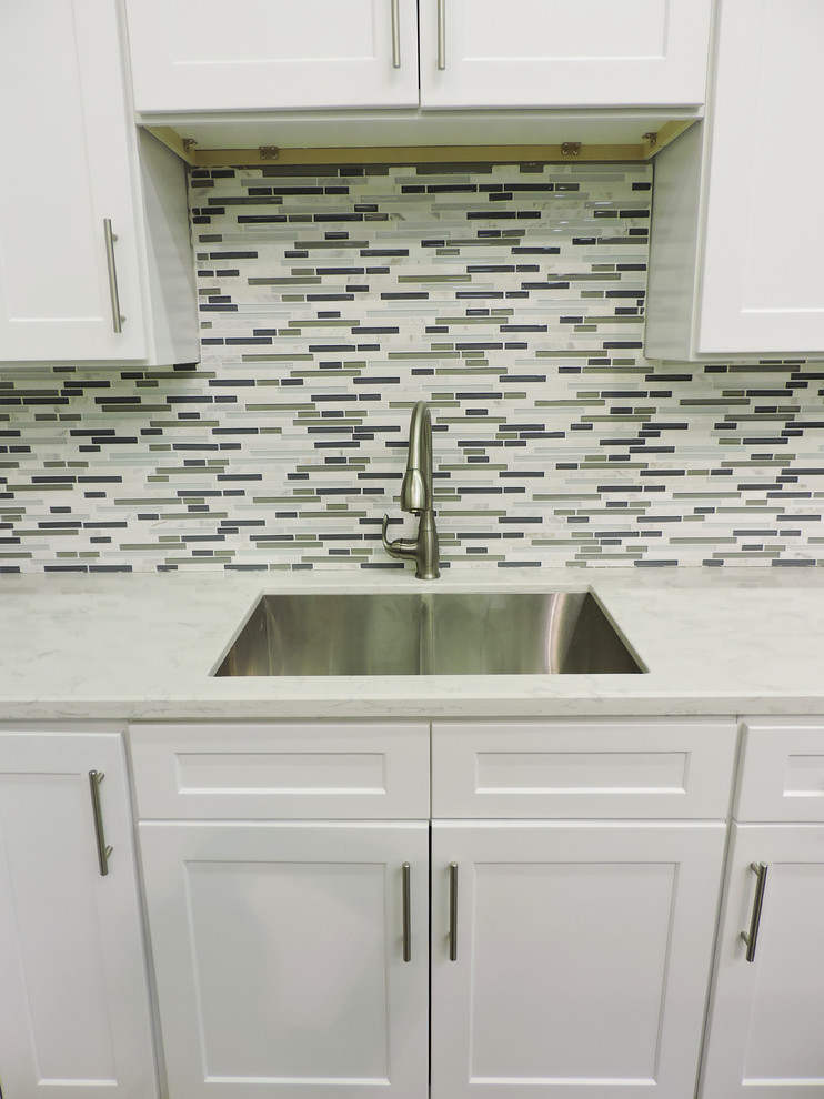 This is an example of a medium sized modern l-shaped kitchen/diner in Louisville with a built-in sink, shaker cabinets, white cabinets, marble worktops, mosaic tiled splashback, stainless steel appliances, light hardwood flooring and no island.