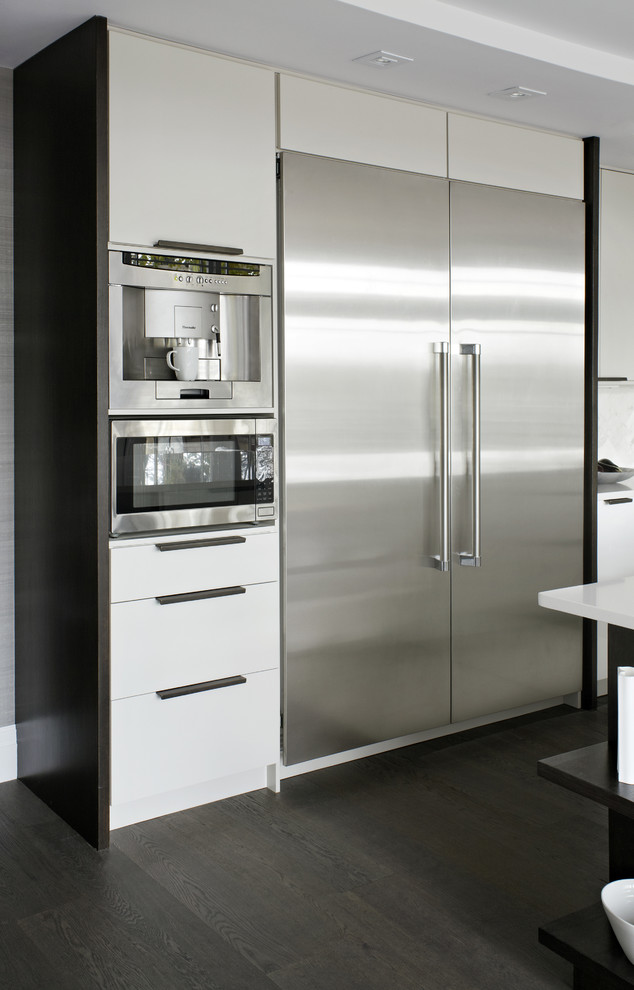 Modern inredning av ett mellanstort kök, med en undermonterad diskho, släta luckor, vita skåp, bänkskiva i kvartsit, vitt stänkskydd, stänkskydd i marmor, rostfria vitvaror, mörkt trägolv, en köksö och brunt golv