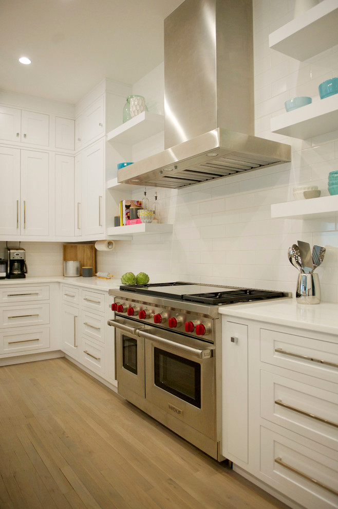 Exempel på ett mellanstort modernt kök, med en undermonterad diskho, skåp i shakerstil, vita skåp, marmorbänkskiva, vitt stänkskydd, stänkskydd i tunnelbanekakel, rostfria vitvaror, ljust trägolv och en köksö