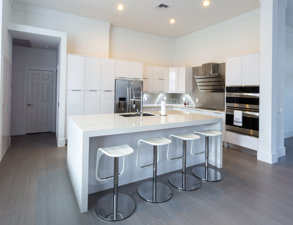 Eat-in kitchen - large modern l-shaped porcelain tile eat-in kitchen idea in Miami with a double-bowl sink, flat-panel cabinets, white cabinets, quartz countertops, metallic backsplash, metal backsplash, stainless steel appliances and an island