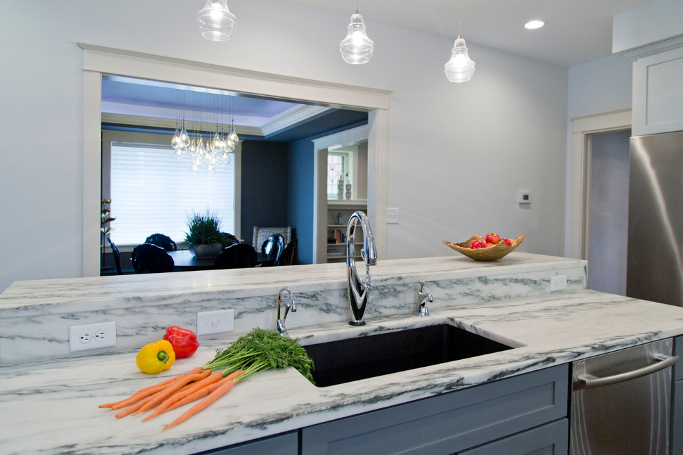 Example of a mid-sized trendy l-shaped dark wood floor and brown floor eat-in kitchen design in St Louis with an undermount sink, raised-panel cabinets, gray cabinets, marble countertops, gray backsplash, ceramic backsplash, stainless steel appliances, an island and black countertops