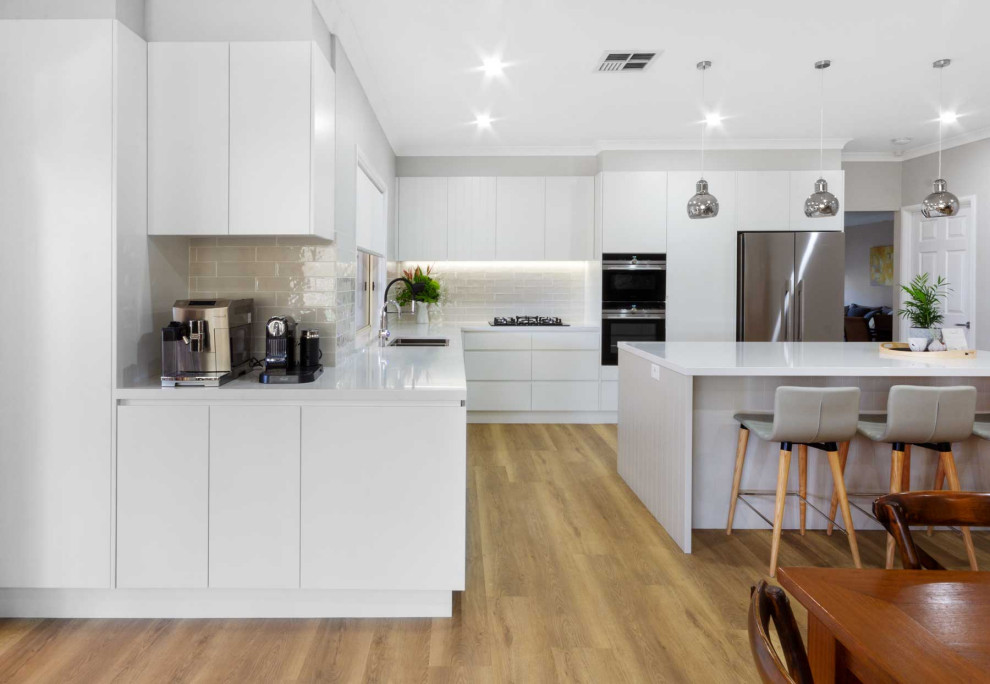 シドニーにあるお手頃価格の中くらいなコンテンポラリースタイルのおしゃれなキッチン (ダブルシンク、フラットパネル扉のキャビネット、白いキャビネット、クオーツストーンカウンター、グレーのキッチンパネル、セラミックタイルのキッチンパネル、黒い調理設備、クッションフロア、茶色い床、白いキッチンカウンター) の写真