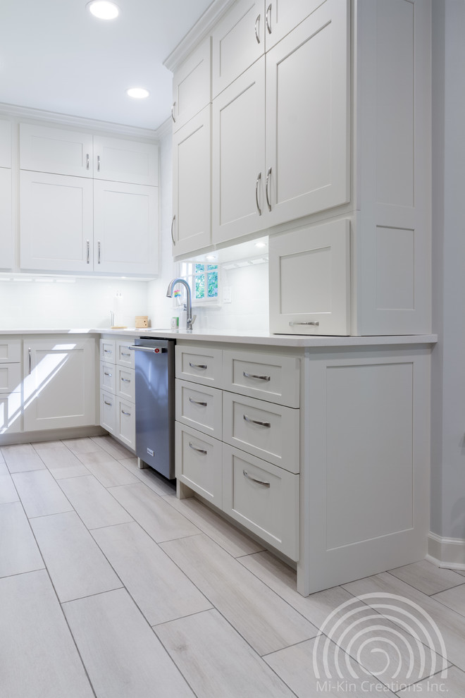 Foto på ett mellanstort funkis vit kök, med en undermonterad diskho, skåp i shakerstil, vita skåp, bänkskiva i kvartsit, vitt stänkskydd, stänkskydd i keramik, rostfria vitvaror, klinkergolv i porslin, en köksö och vitt golv