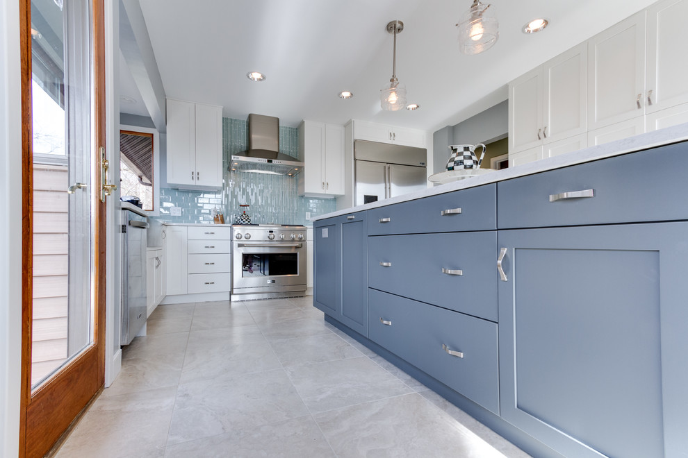 This is an example of a traditional u-shaped kitchen/diner in DC Metro with a belfast sink, shaker cabinets, white cabinets, engineered stone countertops, blue splashback, metro tiled splashback and stainless steel appliances.