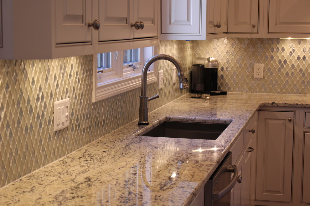 Modern inredning av ett mellanstort kök, med en undermonterad diskho, luckor med upphöjd panel, vita skåp, granitbänkskiva, flerfärgad stänkskydd, stänkskydd i mosaik, rostfria vitvaror och en köksö
