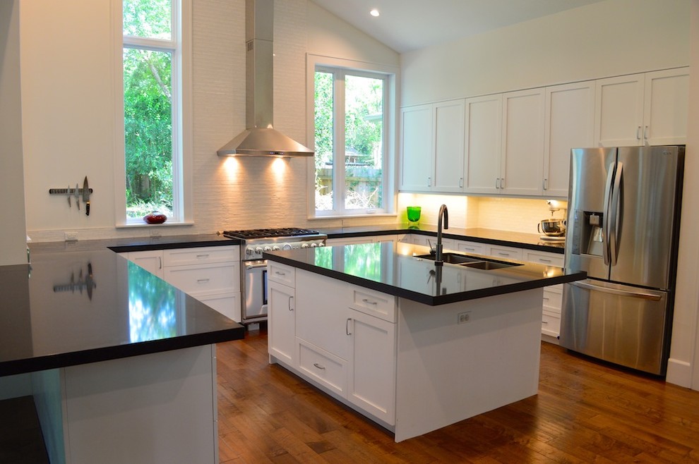 Immagine di una cucina moderna con lavello a doppia vasca, ante in stile shaker, ante bianche, paraspruzzi bianco e elettrodomestici in acciaio inossidabile