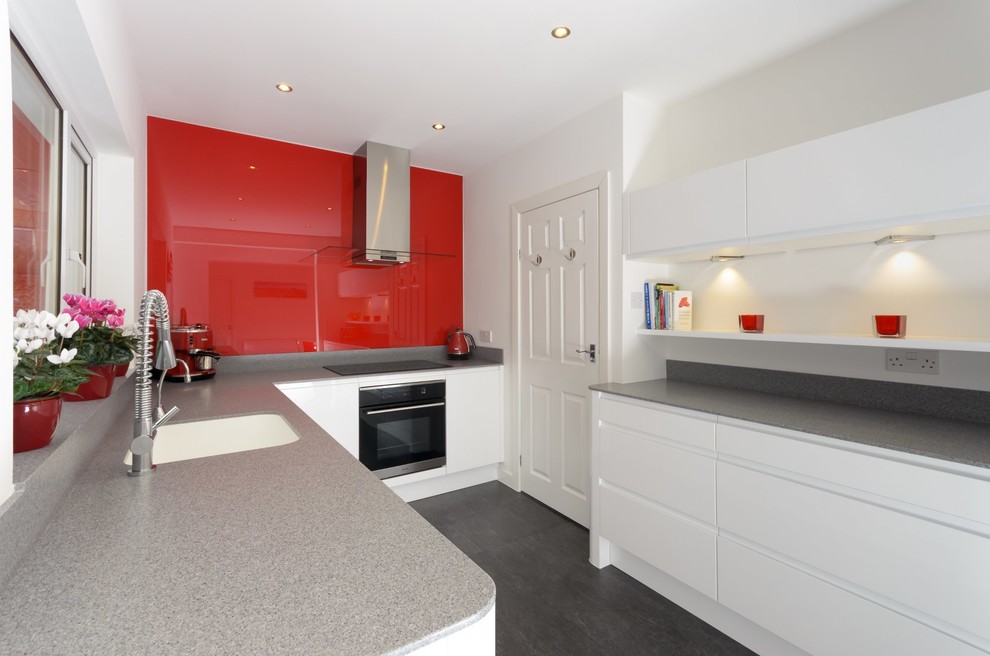 Inspiration for a medium sized contemporary l-shaped kitchen/diner in Sussex with flat-panel cabinets, white cabinets, red splashback, no island and grey worktops.