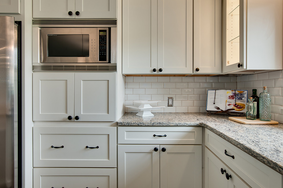 Modern inredning av ett mellanstort kök och matrum, med skåp i shakerstil, vita skåp, rostfria vitvaror, mellanmörkt trägolv och en köksö