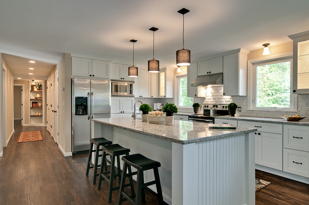 Example of a mid-sized transitional medium tone wood floor eat-in kitchen design in Minneapolis with shaker cabinets, white cabinets, stainless steel appliances and an island