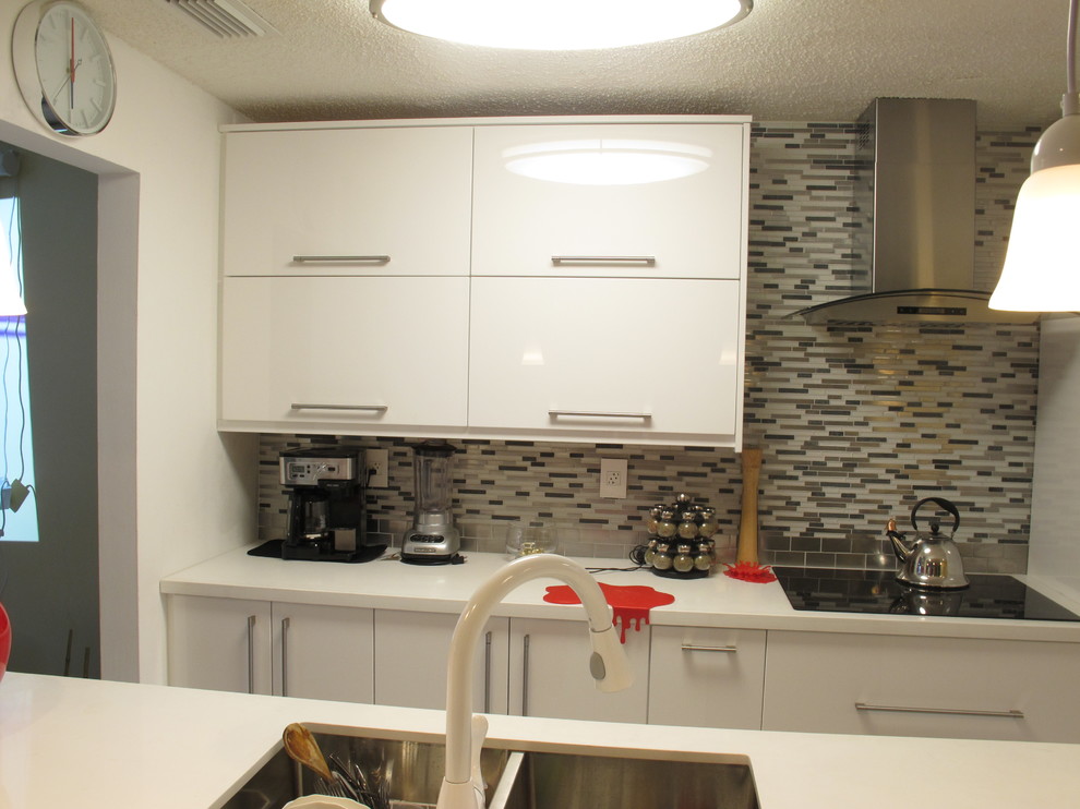 Example of a mid-sized minimalist galley kitchen design in Miami with a double-bowl sink, flat-panel cabinets, white cabinets, multicolored backsplash, glass sheet backsplash, white appliances and a peninsula