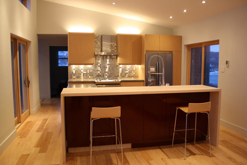 Foto på ett avskilt, mellanstort funkis linjärt kök, med en dubbel diskho, släta luckor, skåp i ljust trä, bänkskiva i betong, flerfärgad stänkskydd, stänkskydd i mosaik, rostfria vitvaror, ljust trägolv, en köksö och brunt golv