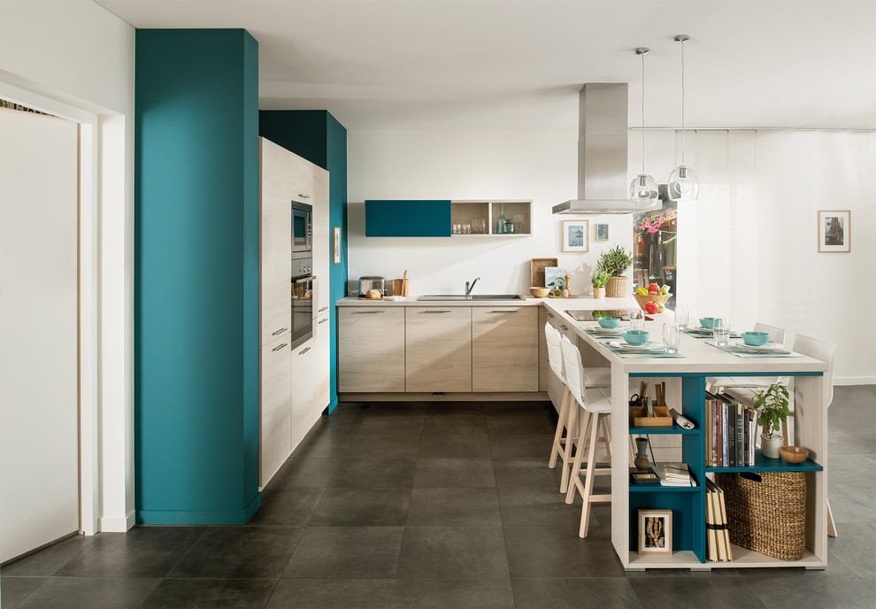 This is an example of a medium sized contemporary l-shaped open plan kitchen in London with flat-panel cabinets, light wood cabinets and a breakfast bar.