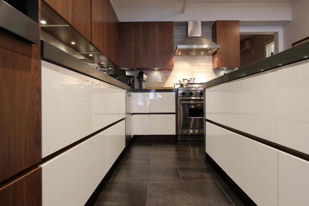 Photo of a small modern l-shaped kitchen in New York with flat-panel cabinets, white cabinets, granite worktops, grey splashback, stainless steel appliances and an island.