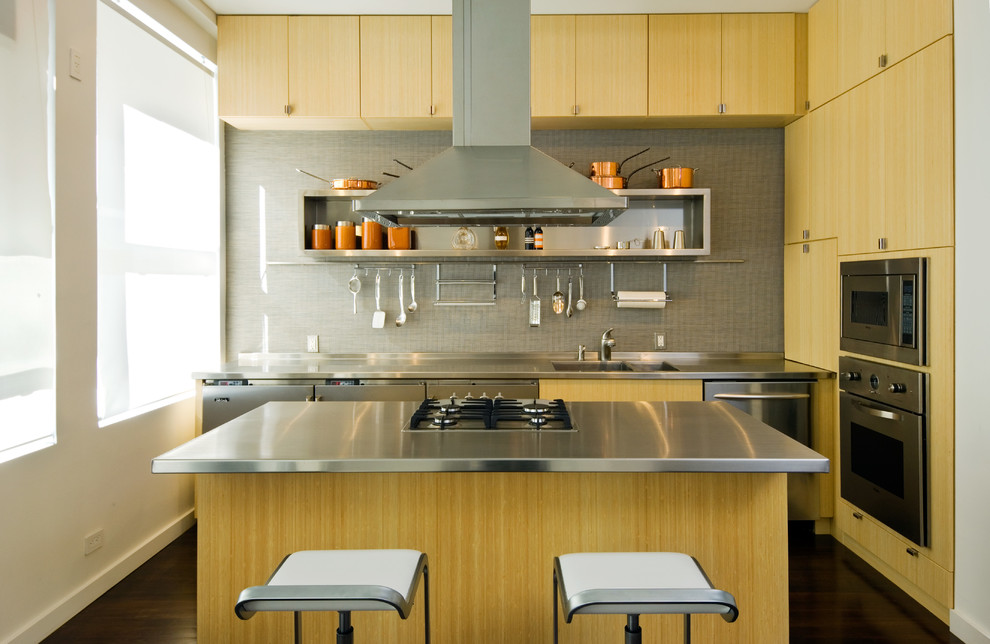 Idéer för små funkis l-kök, med en integrerad diskho, släta luckor, skåp i ljust trä, bänkskiva i rostfritt stål, grått stänkskydd, rostfria vitvaror, mörkt trägolv, en köksö och brunt golv