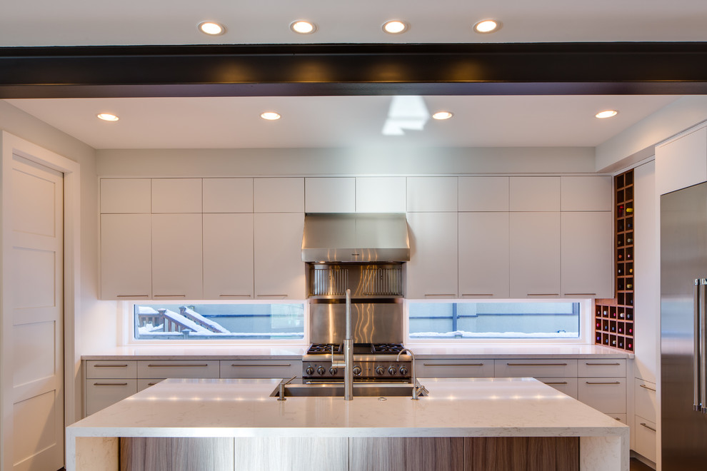 Inspiration for a medium sized modern u-shaped kitchen/diner in Minneapolis with a belfast sink, flat-panel cabinets, white cabinets, engineered stone countertops, white splashback, glass sheet splashback, stainless steel appliances, medium hardwood flooring and an island.