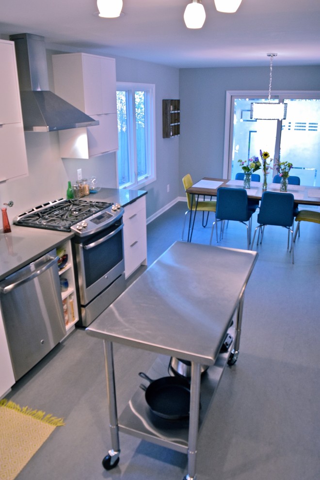 Foto på ett litet funkis kök, med en undermonterad diskho, släta luckor, vita skåp, bänkskiva i kvarts, rostfria vitvaror, linoleumgolv och en köksö