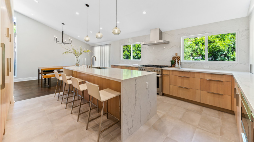 This is an example of a large modern u-shaped kitchen/diner in Los Angeles with a single-bowl sink, light wood cabinets, engineered stone countertops, white splashback, stainless steel appliances, porcelain flooring, an island, beige floors and white worktops.
