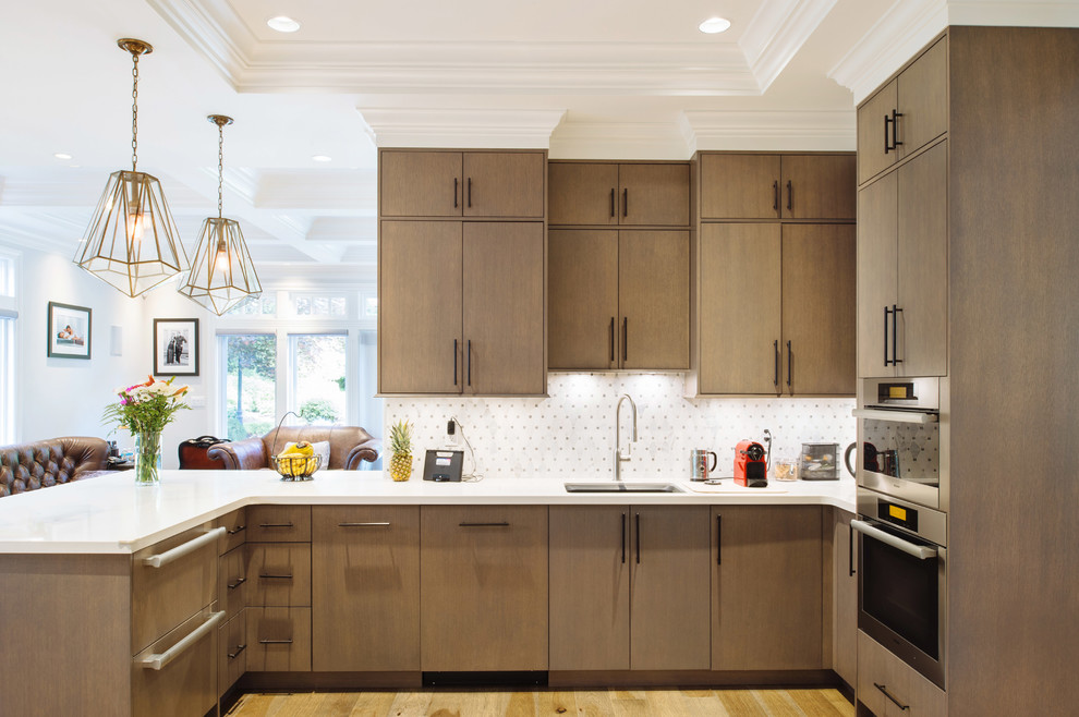 Example of a mid-sized transitional u-shaped medium tone wood floor open concept kitchen design in Vancouver with an undermount sink, flat-panel cabinets, medium tone wood cabinets, white backsplash, mosaic tile backsplash, stainless steel appliances, a peninsula and quartz countertops