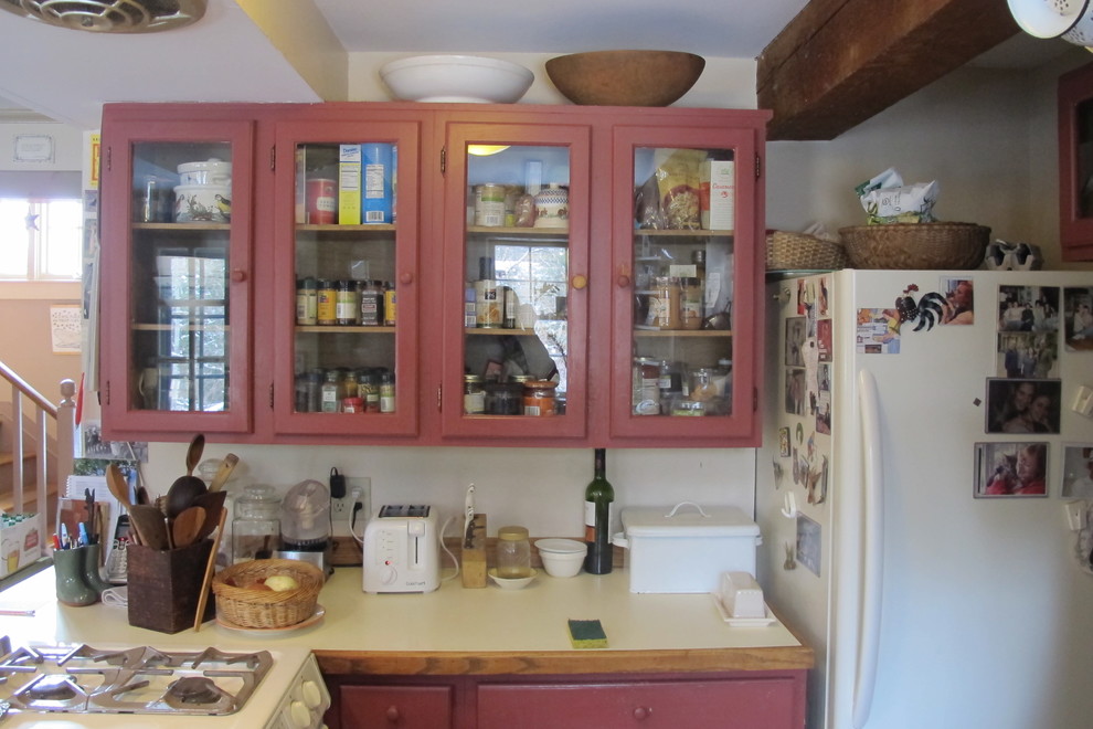 Bild på ett litet lantligt kök, med luckor med profilerade fronter, grå skåp, laminatbänkskiva, brunt stänkskydd, stänkskydd i trä, vita vitvaror och en halv köksö