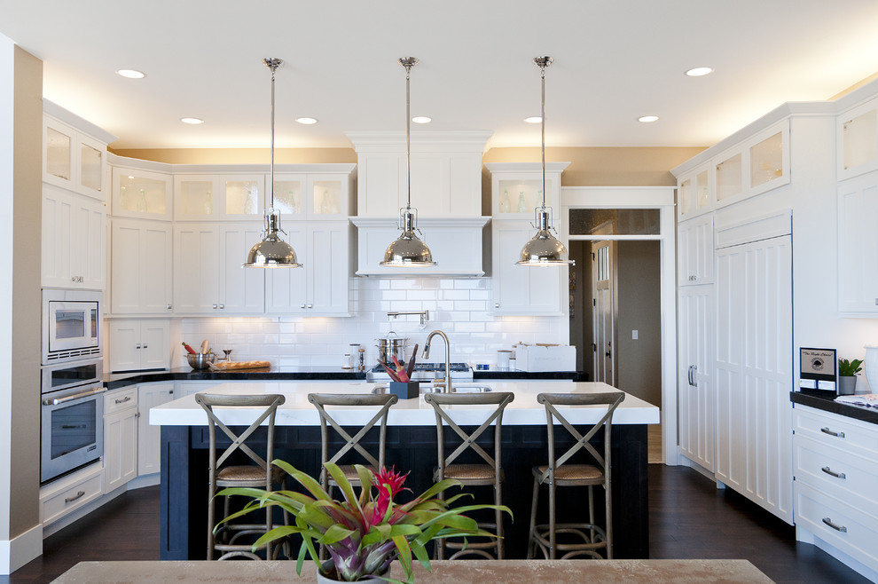 Large arts and crafts l-shaped dark wood floor eat-in kitchen photo in Salt Lake City with an undermount sink, recessed-panel cabinets, white cabinets, marble countertops, white backsplash, subway tile backsplash, stainless steel appliances and an island