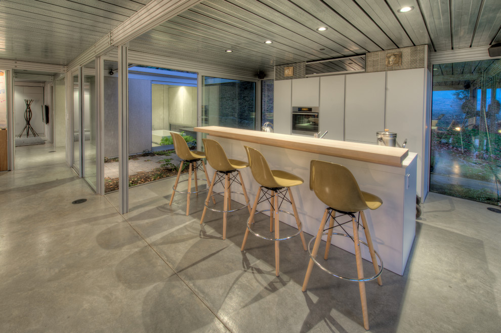 Свежая идея для дизайна: параллельная кухня в стиле лофт с деревянной столешницей, плоскими фасадами и белыми фасадами - отличное фото интерьера