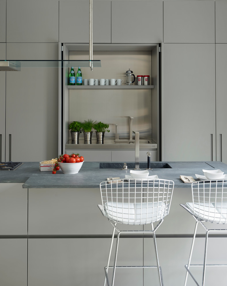 Moderne Küche mit Unterbauwaschbecken, flächenbündigen Schrankfronten, grauen Schränken, Küchenrückwand in Grau und Kücheninsel in London