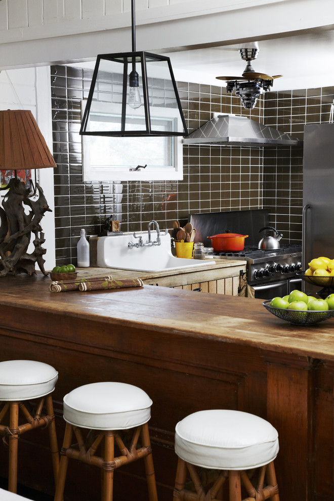 Rustik inredning av ett kök, med stänkskydd i tunnelbanekakel, en rustik diskho, träbänkskiva och brunt stänkskydd