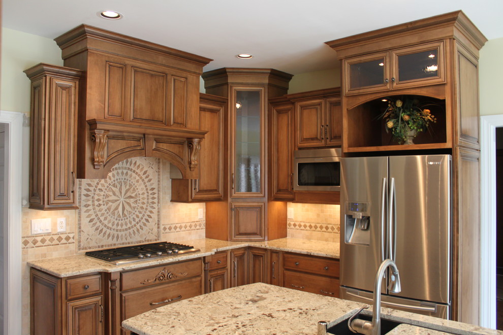 Aménagement d'une cuisine américaine classique en bois brun avec un évier encastré, un placard avec porte à panneau surélevé, un plan de travail en granite et un électroménager en acier inoxydable.