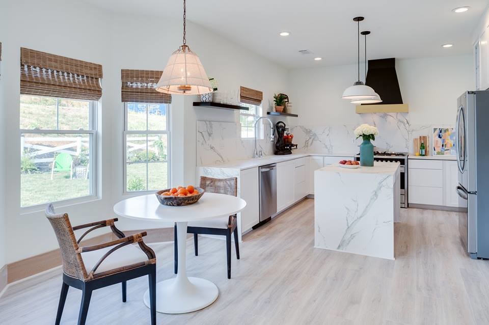 Modern inredning av ett mellanstort kök, med en undermonterad diskho, släta luckor, vita skåp, marmorbänkskiva, vitt stänkskydd, rostfria vitvaror, vinylgolv och en köksö