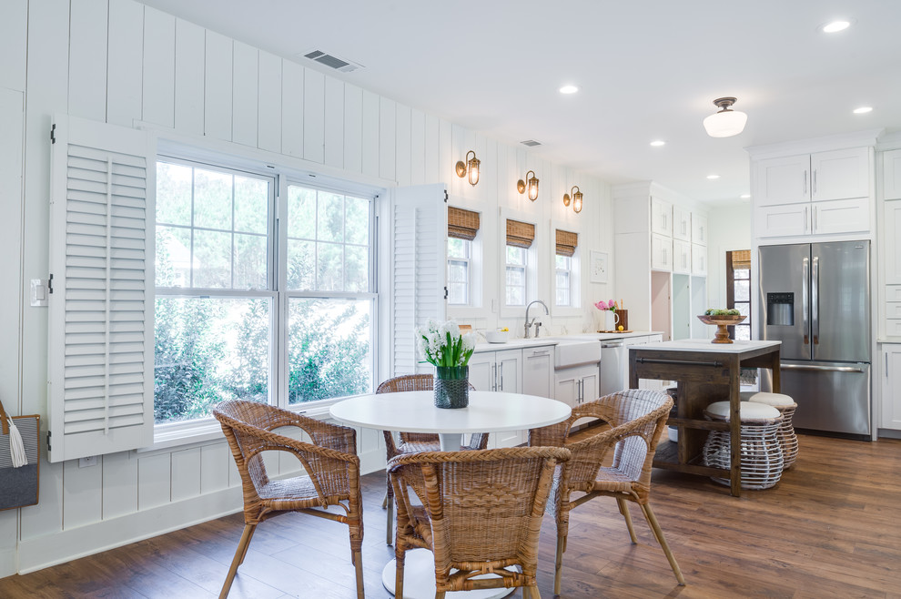 Inspiration pour une grande cuisine américaine design en U avec un évier de ferme, un placard à porte shaker, des portes de placard blanches, une crédence blanche, une crédence en bois, un électroménager en acier inoxydable, parquet foncé, îlot, un sol marron et un plan de travail blanc.