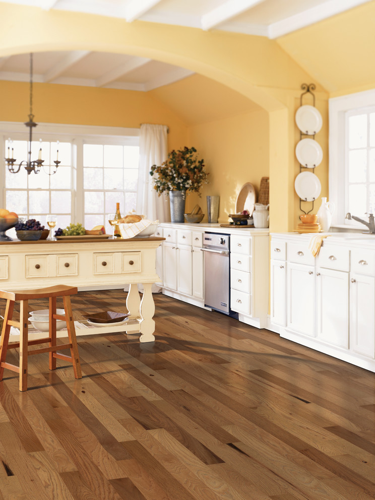 Foto på ett stort lantligt linjärt kök och matrum, med en nedsänkt diskho, luckor med infälld panel, vita skåp, bänkskiva i koppar, rostfria vitvaror, mörkt trägolv och en köksö