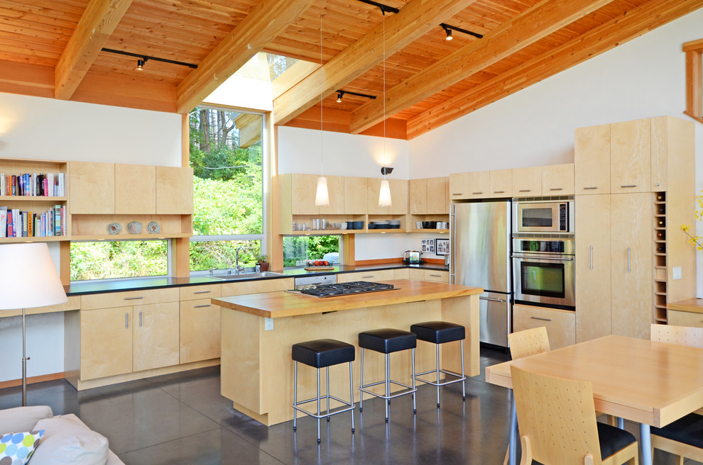 Design ideas for a contemporary l-shaped open plan kitchen in Seattle with stainless steel appliances, wood worktops, flat-panel cabinets and light wood cabinets.