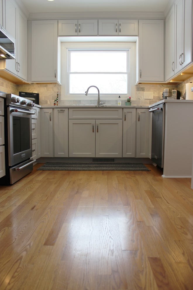 Idéer för att renovera ett mellanstort vintage vit vitt u-kök, med en undermonterad diskho, släta luckor, vita skåp, bänkskiva i kvarts, grått stänkskydd, stänkskydd i marmor, rostfria vitvaror, ljust trägolv och en halv köksö