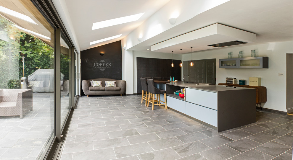 ロンドンにある高級な広いコンテンポラリースタイルのおしゃれなキッチン (ドロップインシンク、フラットパネル扉のキャビネット、濃色木目調キャビネット、珪岩カウンター、ベージュキッチンパネル、パネルと同色の調理設備、セラミックタイルの床) の写真