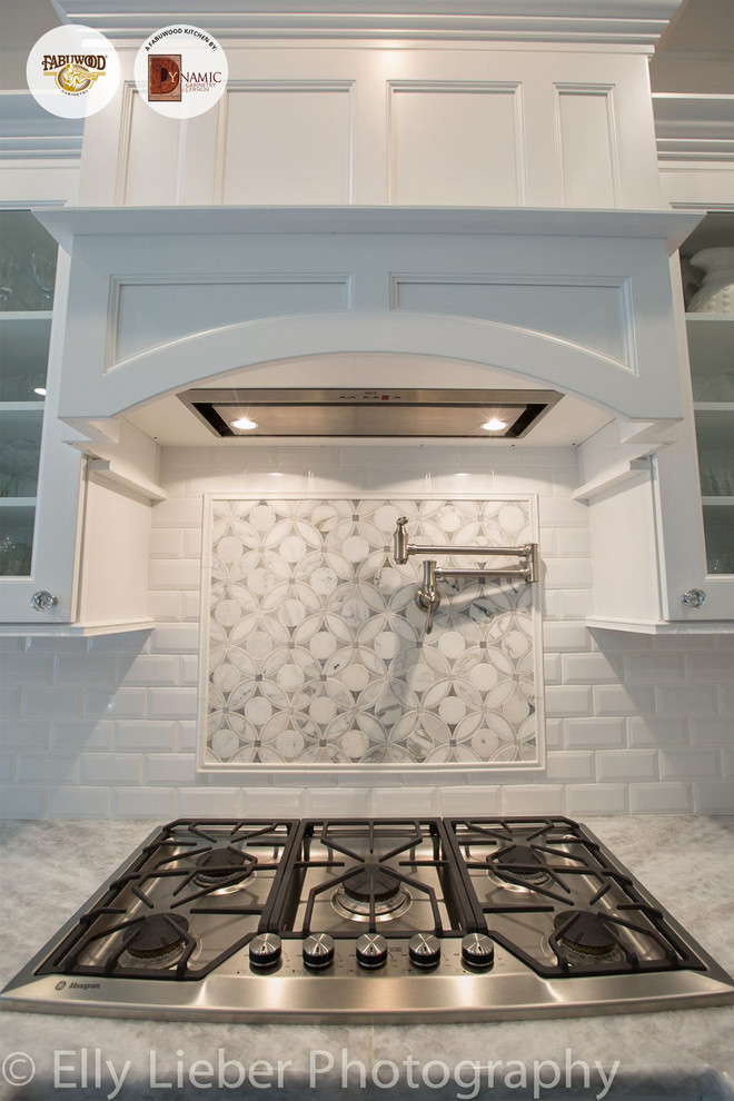 Aménagement d'une grande cuisine américaine contemporaine avec des portes de placard blanches, une crédence blanche et un électroménager en acier inoxydable.