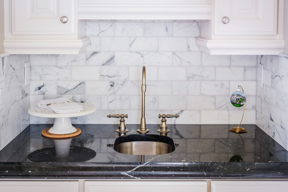 Esempio di una cucina classica di medie dimensioni con lavello sottopiano, ante di vetro, ante bianche, top in granito, paraspruzzi bianco, paraspruzzi in marmo, elettrodomestici in acciaio inossidabile, parquet scuro, pavimento marrone e top nero