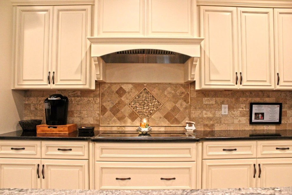 Immagine di una cucina chic con lavello sottopiano, ante con bugna sagomata, top in granito, paraspruzzi con piastrelle in pietra e elettrodomestici in acciaio inossidabile
