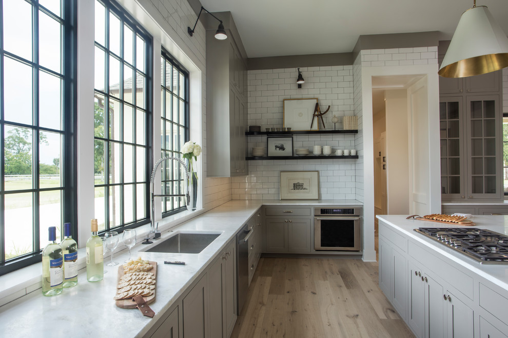 Inspiration for a huge eclectic u-shaped light wood floor and white floor open concept kitchen remodel in Other with an undermount sink, shaker cabinets, gray cabinets, marble countertops, white backsplash, subway tile backsplash, paneled appliances and an island