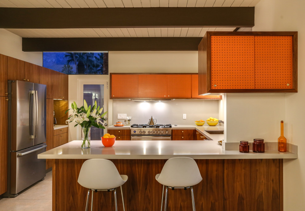 1960s u-shaped concrete floor, beige floor, exposed beam and shiplap ceiling eat-in kitchen photo in Other with an undermount sink, flat-panel cabinets, medium tone wood cabinets, quartz countertops, white backsplash, stainless steel appliances, a peninsula and beige countertops