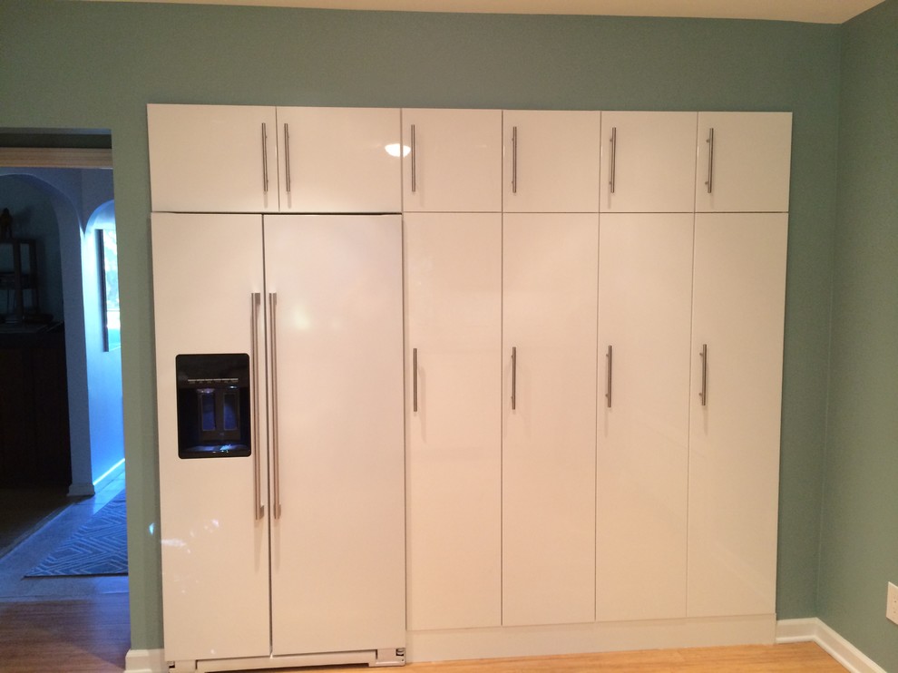 Example of a mid-sized trendy l-shaped bamboo floor enclosed kitchen design in Newark with an undermount sink, flat-panel cabinets, white cabinets, quartz countertops, gray backsplash, mosaic tile backsplash and white appliances
