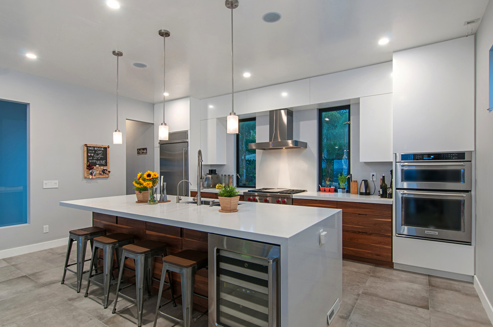 Zweizeilige, Mittelgroße Moderne Küche mit flächenbündigen Schrankfronten, weißen Schränken, Quarzwerkstein-Arbeitsplatte, Küchengeräten aus Edelstahl, Zementfliesen für Boden, Kücheninsel und grauem Boden in San Diego