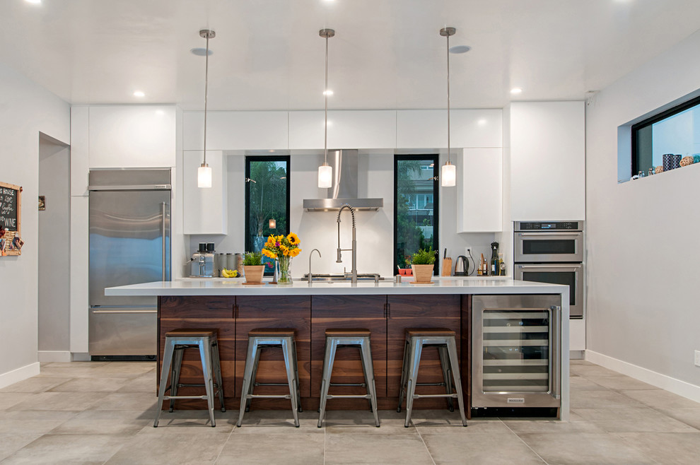 This is an example of a medium sized modern galley enclosed kitchen in San Diego with flat-panel cabinets, white cabinets, engineered stone countertops, stainless steel appliances, cement flooring, an island and grey floors.