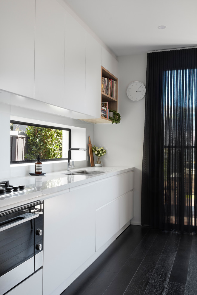 Design ideas for a large contemporary single-wall kitchen/diner in Melbourne with a double-bowl sink, white splashback, dark hardwood flooring, black floors and white worktops.