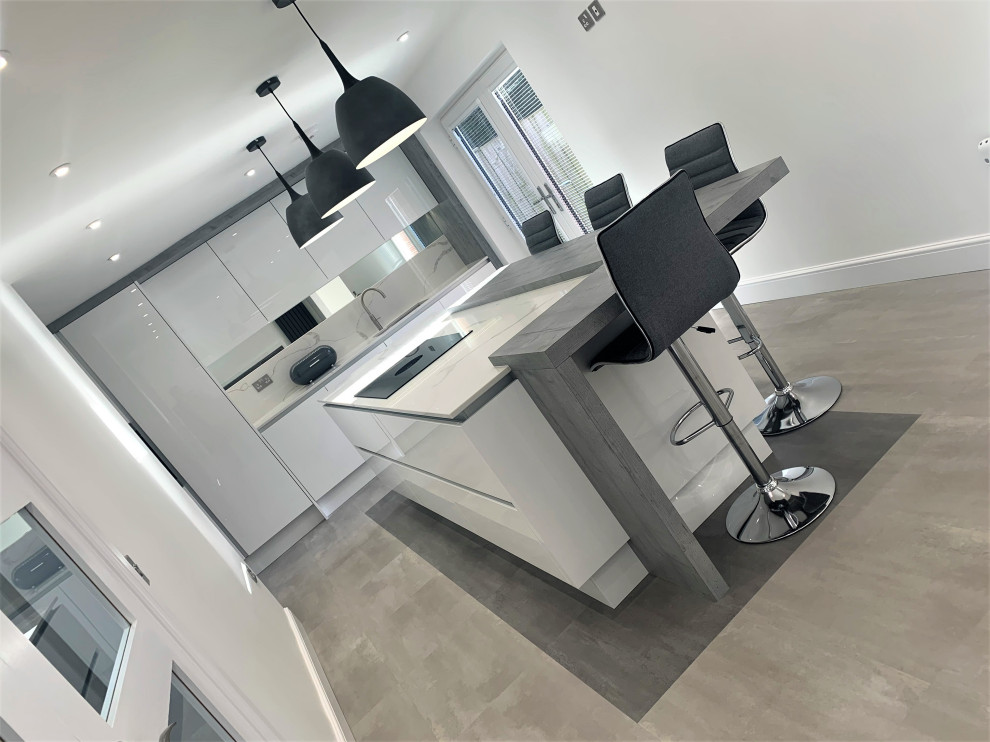 Photo of a medium sized contemporary single-wall kitchen/diner in Other with a single-bowl sink, flat-panel cabinets, grey cabinets, engineered stone countertops, white splashback, stainless steel appliances, vinyl flooring, an island and white worktops.