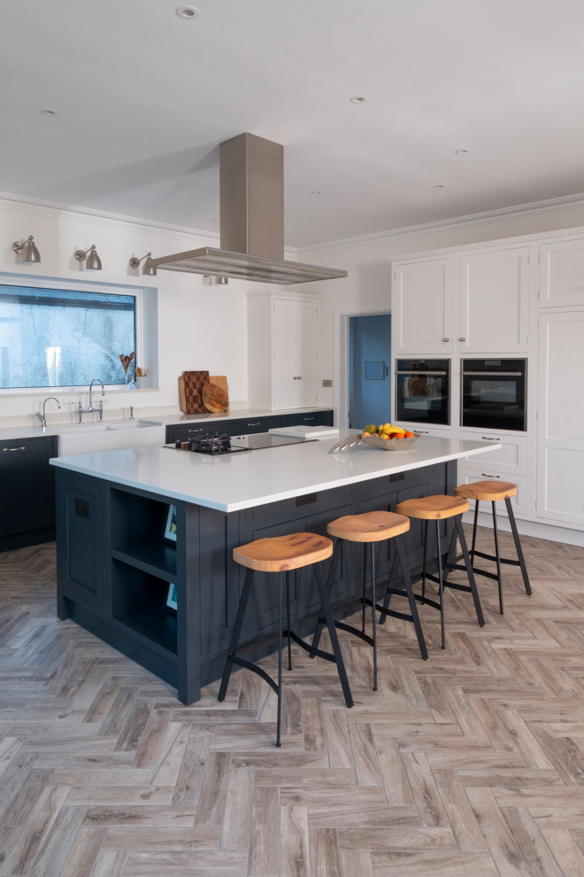 Example of a large classic l-shaped beige floor kitchen design in Cardiff with a farmhouse sink, shaker cabinets, white cabinets, paneled appliances, an island and white countertops
