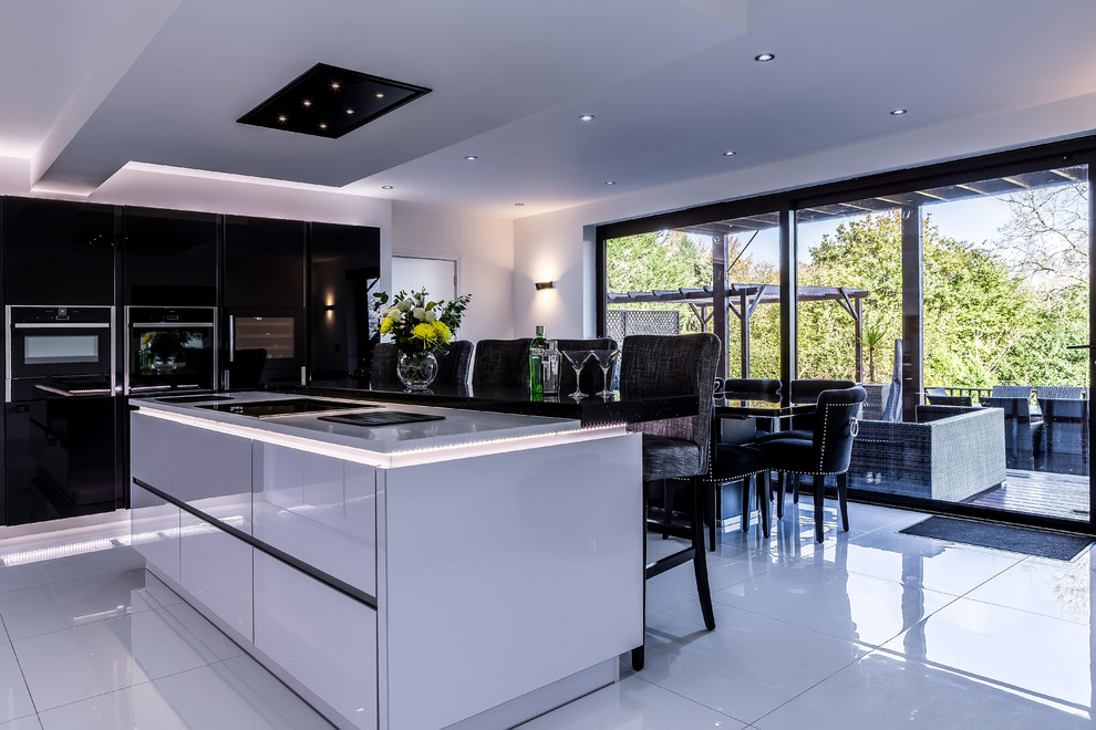 Design ideas for a medium sized contemporary kitchen/diner in Cardiff with a built-in sink, flat-panel cabinets, composite countertops, black splashback, an island and white floors.