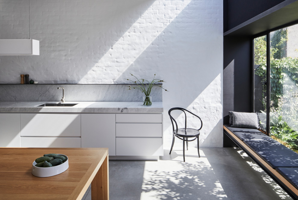 Idee per una cucina abitabile moderna con lavello sottopiano, ante lisce, ante bianche, top in marmo, paraspruzzi grigio, paraspruzzi in marmo, pavimento in cemento, pavimento grigio e top grigio