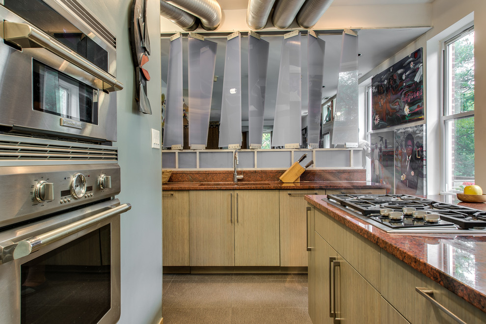 Cette image montre une cuisine design en bois clair avec un placard à porte plane et un électroménager en acier inoxydable.